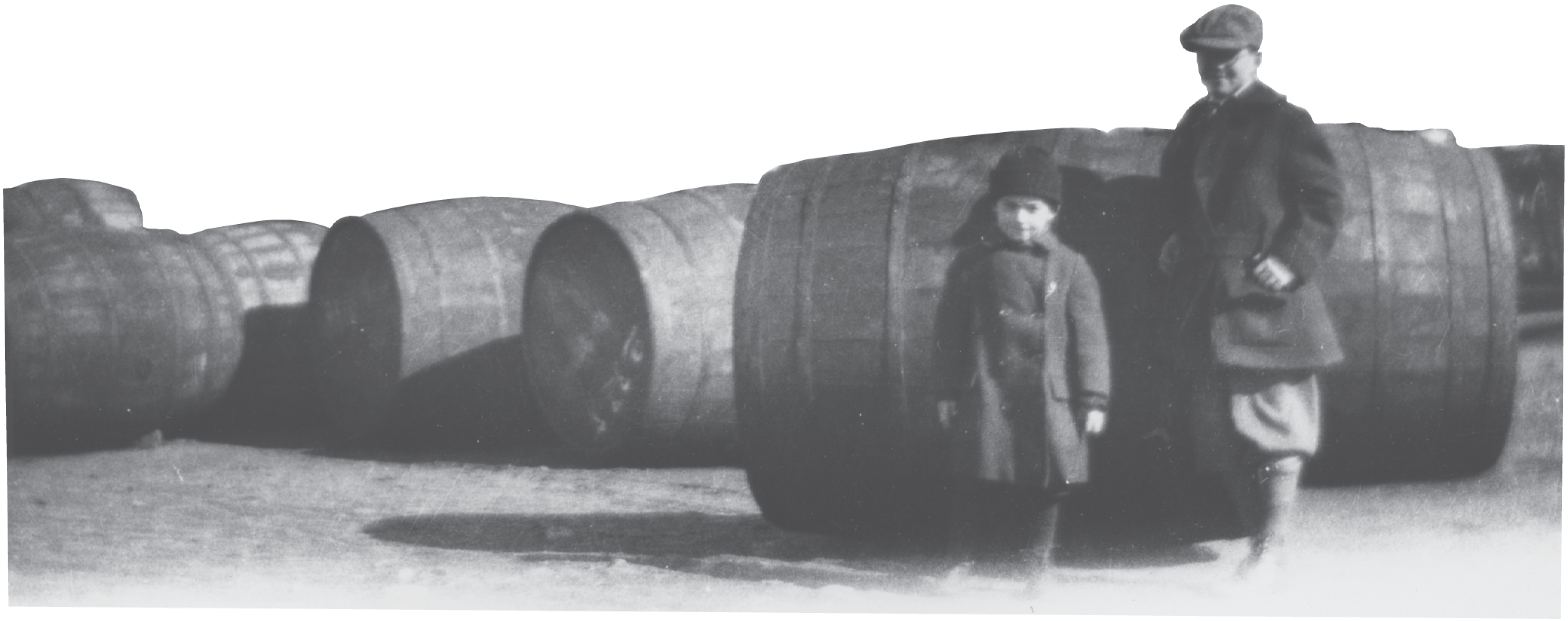 Two young boys stand in front of barrels of whale oil